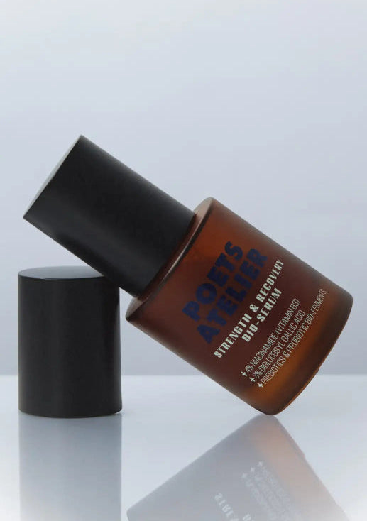 A sleek amber glass bottle with a black cap, labeled ’poets & quill strength & rejuvenate dro-seer,’ featuring bold blue lettering and minimalist design.