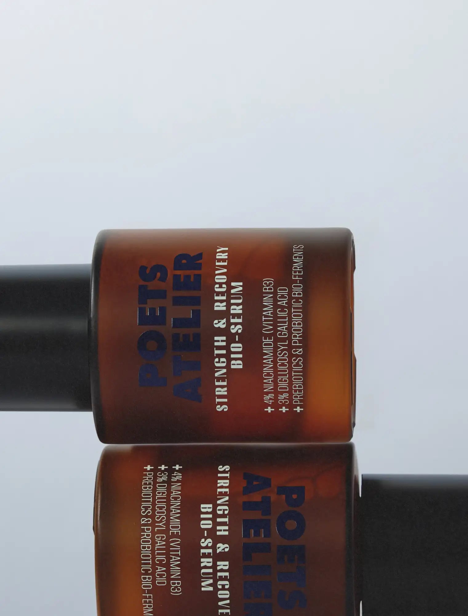 Amber glass bottle with black pump and label reading ’poets atelier strength & recovery bio-serum’