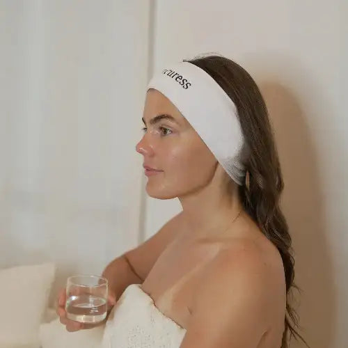 White headband with black embroidered text reading ’wellness’