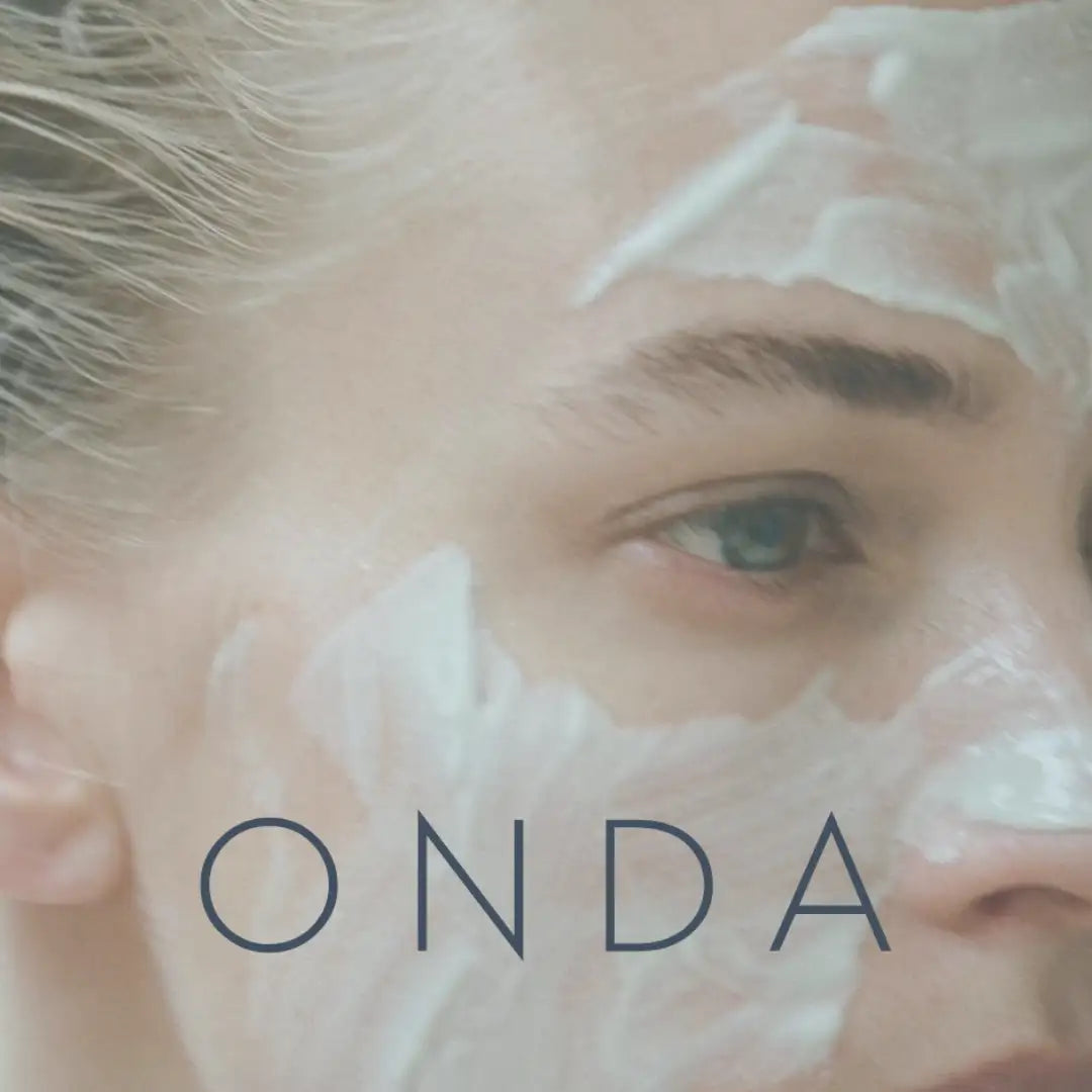 A woman’s face with a white, creamy facial mask applied to her skin.